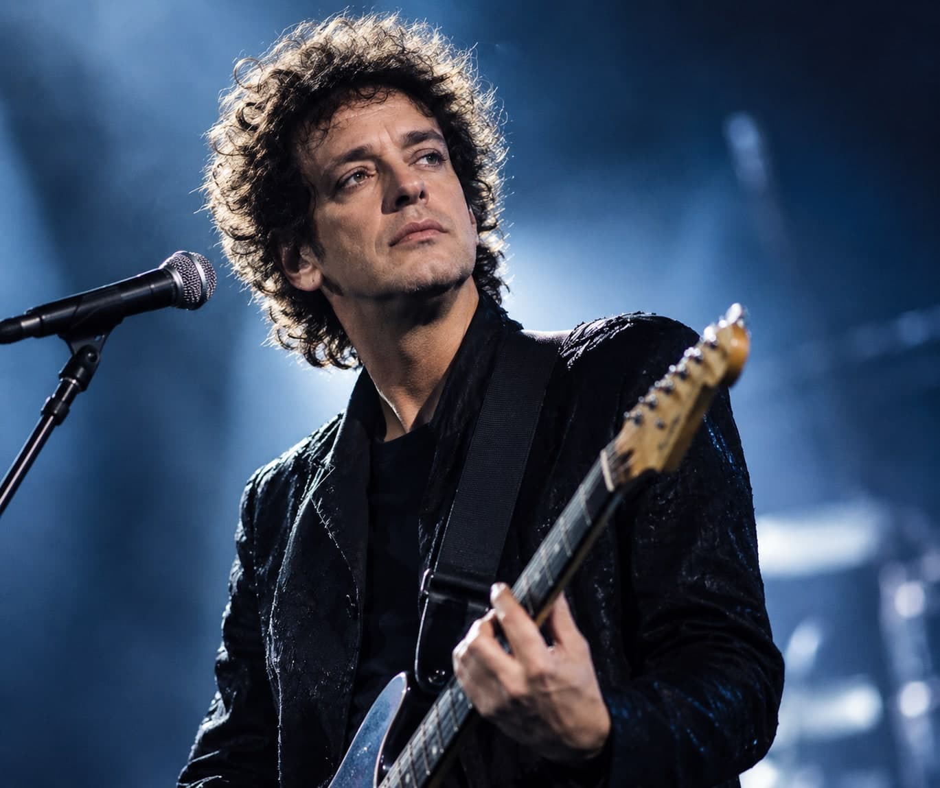 Gustavo Cerati ao vivo, guitarra na mão, luz azul de palco ao fundo